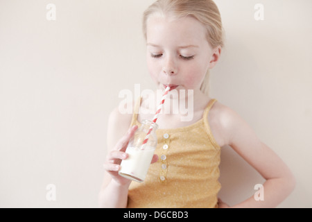 Young girl drinking glass of milk through straw Stock Photo