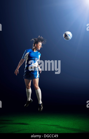 Young female soccer player heading ball Stock Photo