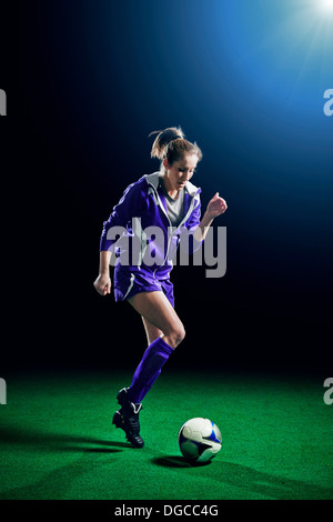 Female soccer player running with ball Stock Photo