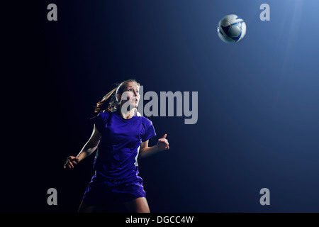 Young female soccer player heading ball Stock Photo