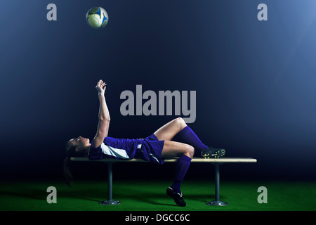 Female soccer player lying on bench Stock Photo