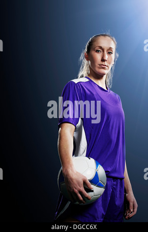 Studio shot of young female soccer player holding ball Stock Photo