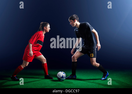 Male and female soccer players with ball Stock Photo