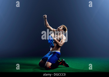 Male soccer player kneeling with arm raised Stock Photo