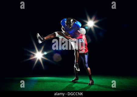American football players jumping with ball Stock Photo