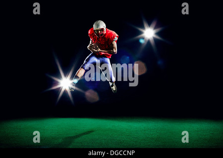 American football player mid air holding ball Stock Photo