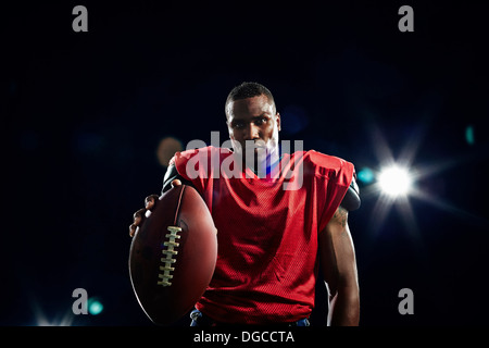 Portrait of american football player holding ball Stock Photo