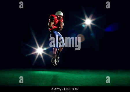 American football player mid air with ball Stock Photo