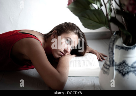 Young female reading book while lying on floor Stock Photo