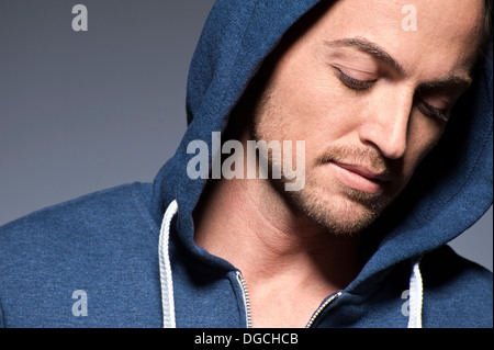 Young man wearing hood and looking down Stock Photo