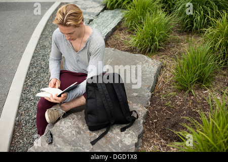 Young man studying text book in park Stock Photo