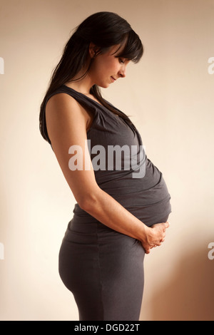 Pregnant woman meditating whilst holding abdomen Stock Photo