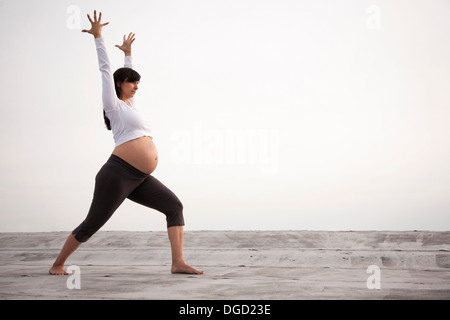 Pregnant woman in yoga warrior pose Stock Photo