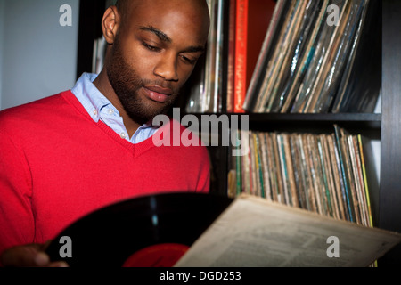 Portrait of young man removing vinyl record from sleeve Stock Photo