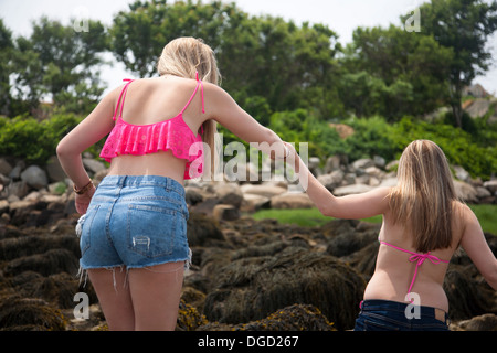 Young woman holding hands with friend on beach, rear view Stock Photo
