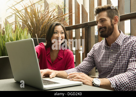Young business colleagues looking at laptop in meeting Stock Photo