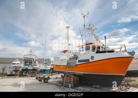 Small fishing boats lay on the coast in Norwegian wharf under cloudy sky Stock Photo