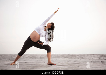 Pregnant woman in yoga lunging pose Stock Photo