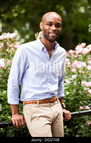 Portrait of young man leaning on railings in park