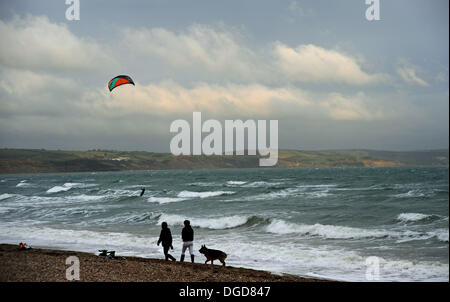 Walkers and kite surfers make the most of the  blustery conditions in Weymouth Bay early this evening as stormy weather moves in Stock Photo