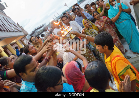 Devotees taking heat of the sacred fire from the Aarti, Evening Ganga Aarti at the Parmarth Niketan Ashram in Rishikesh, India Stock Photo