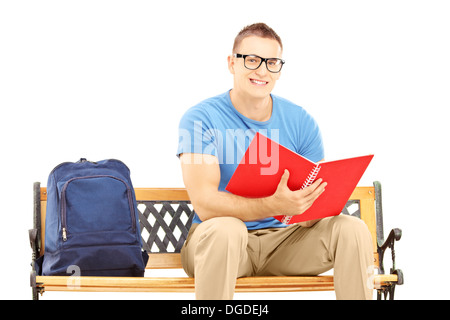 Smiling male student sitting on a wooden bench and reading a book Stock Photo