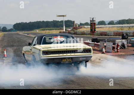 dodge muscle car doing a static burnout in the water box before a race Stock Photo