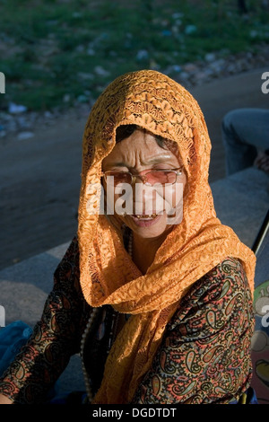 A woman fortune teller wearing a headscarf is working on the riverside promenade in Phnom Penh, Cambodia. Stock Photo