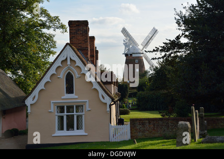 Thaxted Windmill pictured in distance beyond typical English Almshouse & gravestones in grounds of Thaxted Parish Church, Essex. Stock Photo
