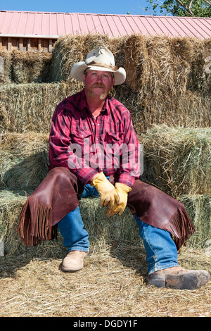 Cowboy from Rimrock rodeo sitting on straw bales, Rimrock, Grand Junction, Colorado, USA Stock Photo