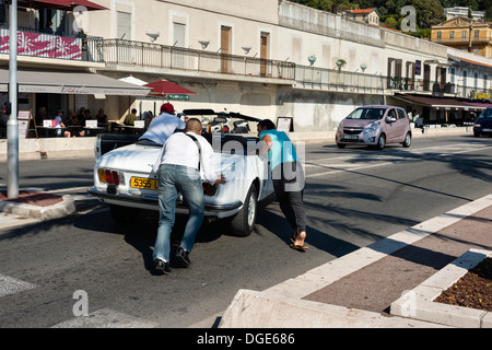 Men pushing a broken down car on Promanade des Anglais, Nice Stock Photo