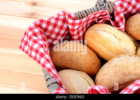 Detail of fresh bread rolls in a rustic picnic basket lined with red gingham Stock Photo