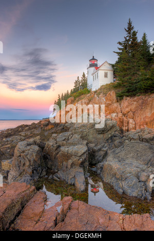 Bass Harbor Head Lighthouse is reflected in a tidal pool shortly before sunrise as it overlooks the entrance to Bass Harbor in Acadia National Park. Stock Photo