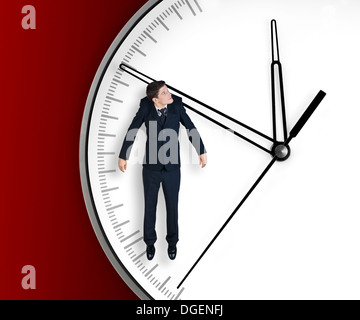 Businessman hangs on an arrow of clock, isolated on red background Stock Photo