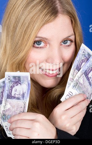 Young Happy Successful Blonde Caucasian Business Woman Holding A Fan Of British Banknotes Money, Alone And Isolated Against A Blue Background Stock Photo