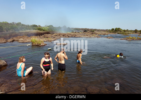Tourists swimming out to Devils Pool at the edge of the Victoria Falls, Livingstone Island, Zambia africa Stock Photo