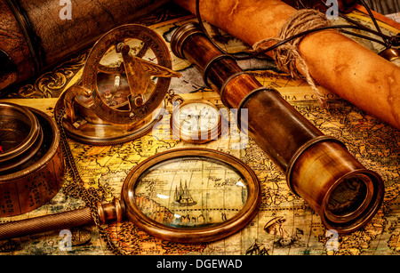 Vintage magnifying glass, compass, telescope and a pocket watch lying on an old map. Stock Photo