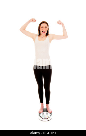 a girl on a weighing scale, celebrating her success of loosing weight Stock Photo