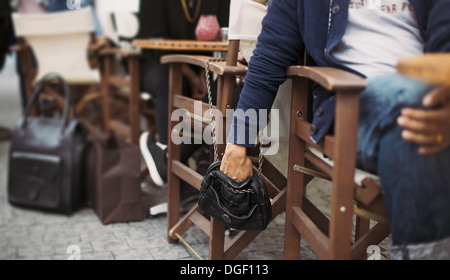 Man stealing wallet from the woman's purse at street cafe during daytime. Pickpocketing at the street cafe Stock Photo