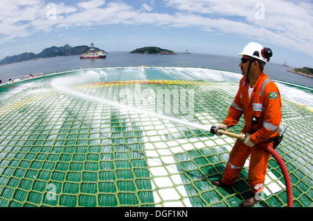 Oil rig crew members checking the foam cannons at the helicopter landing deck at OCEAN RIG MYKONOS drilling ship. Stock Photo