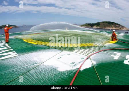 Oil rig crew members checking the foam cannons at the helicopter landing deck at OCEAN RIG MYKONOS drilling ship. Stock Photo