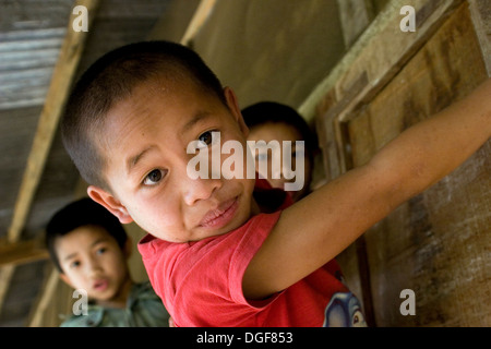 A group of young boys are playing on the door of their sparse classroom  in Ban Bumlao, Luang Prabang Province, Laos. Stock Photo
