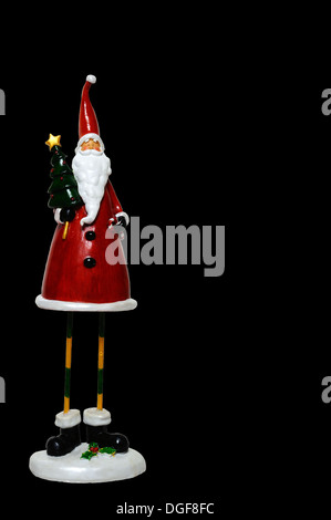 Father Christmas statue against a black background. Stock Photo
