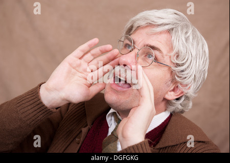 Grey haired old man using his hands to shout louder. Stock Photo