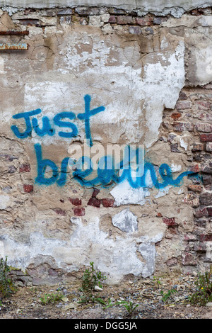 'Just breathe' graffiti advice on a decaying, derelict wall with exposed brick and crumbling plaster in Berlin Stock Photo