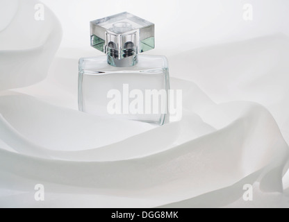 perfume bottles, empty, alone, is buried in the folds of the air, clouds of white cloth Stock Photo
