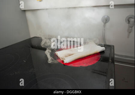 Towel lying on a hot plate demonstrating 'fire causes', such as kitchen fires, Stuttgart, Baden-Wuerttemberg Stock Photo
