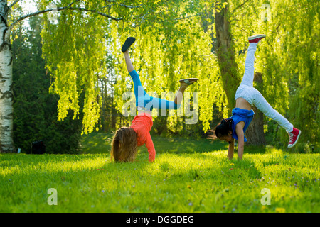 Two girls doing handstands in park Stock Photo