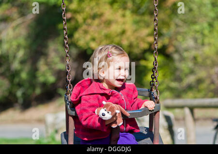 Little girl laughing on a swing, Wuerzburg, Bavaria Stock Photo