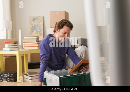 Mature man sitting on floor looking at unpacked picture Stock Photo
